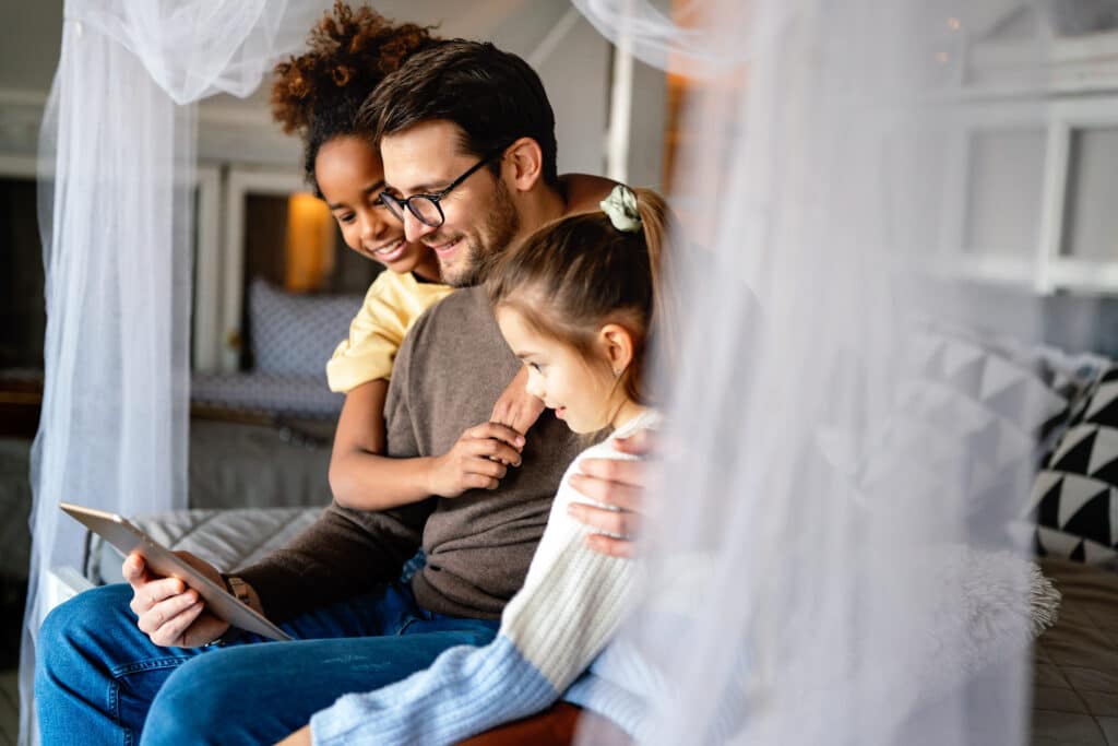 Multiethnic happy children and father studying at home for online school